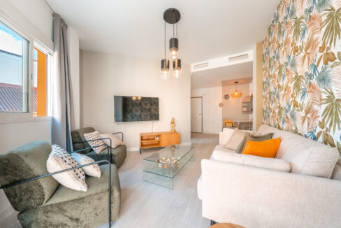 Stylish living room with sofa, tv and 2 chairs with exterior view of apartment in Malaga centre.