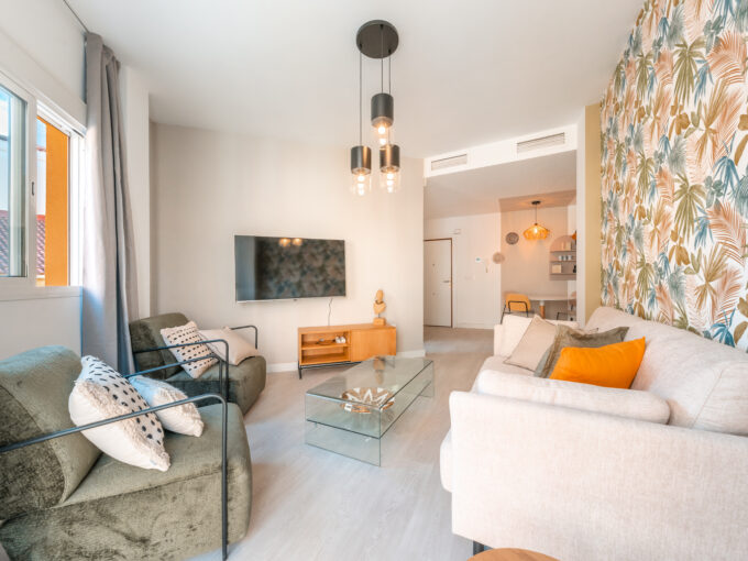 Stylish living room with sofa, tv and 2 chairs with exterior view of apartment in Malaga centre.