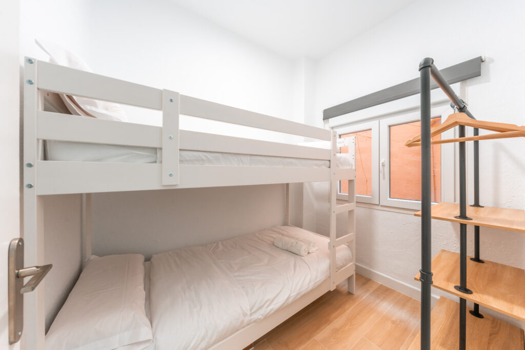 Second bedroom with bunk bed and open wardrobe of cosy apartment with patio in Malaga