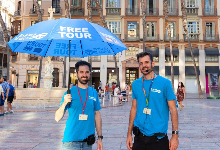 Two guides of free walking tour Malaga with blue umbrella